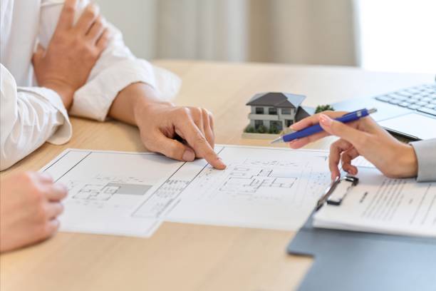 Two individuals seated at a table, examining blueprints and papers, engaged in a collaborative discussion about home remodeling with a general contractor in San Mateo.