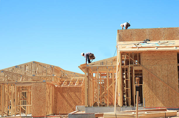 A construction site featuring a man working on the roof, surrounded by scaffolding and building materials—expert work by general contractors in San Mateo CA.