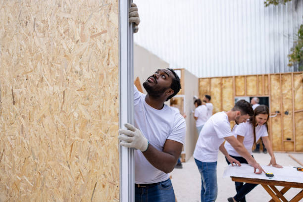 A man holds a wooden frame while another works on it, showcasing teamwork and craftsmanship—expertly handled by general contractors in San Mateo CA.