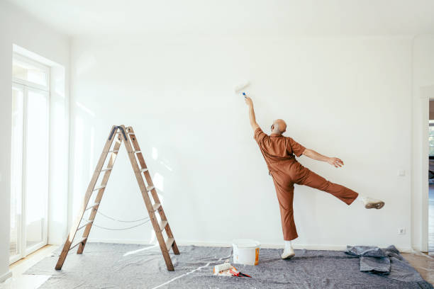 Young man coloring the wall of a living room during a home renovation project, part of whole home remodeling.