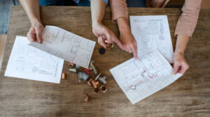 Hillsborough kitchen remodeling: Two individuals examining architectural plans spread out on a table, engaged in a focused discussion.