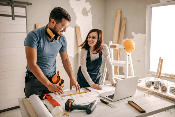 A man and woman collaborate on a home remodeling project together in a cozy home setting, focused and engaged in their work.