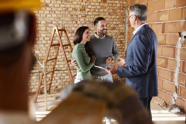 Young happy couple communicating with their real estate agent at a construction site for the best remodeling company in San Francisco.