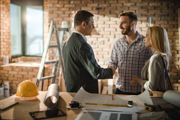 A man and woman shake hands in front of a textured brick wall, symbolizing agreement and collaboration with the best remodeling company in San Francisco.