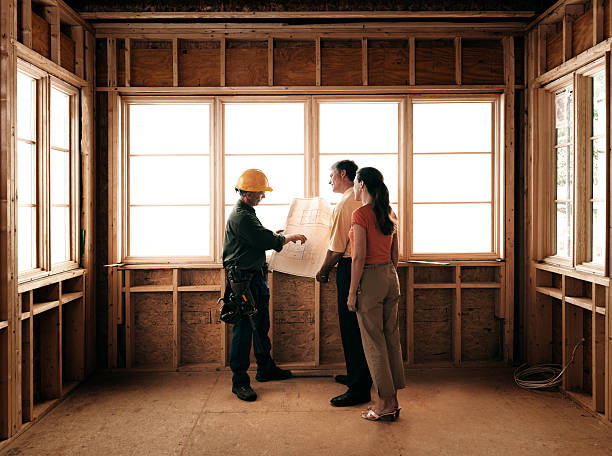 Two people stand in an unfinished room during a home remodeling project in San Francisco, with a large window letting in natural light, showcasing the design's focus on light, space, and modern craftsmanship