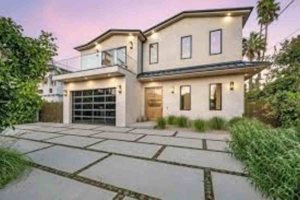 A new home in the evening, featuring a well-lit driveway, highlighting its architectural design and inviting atmosphere.